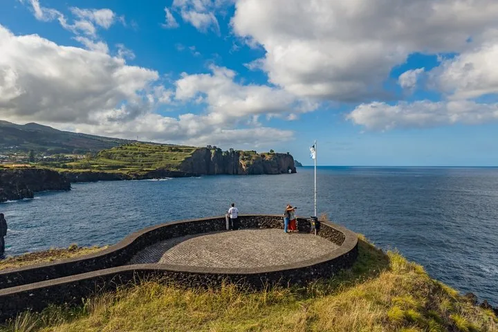Two people at a stone viewpoint looking out at the ocean coastline.